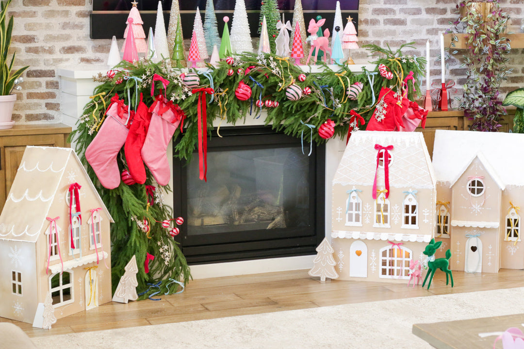 Several faux gingerbread houses sitting in front of fireplace with décor trees on mantel above.